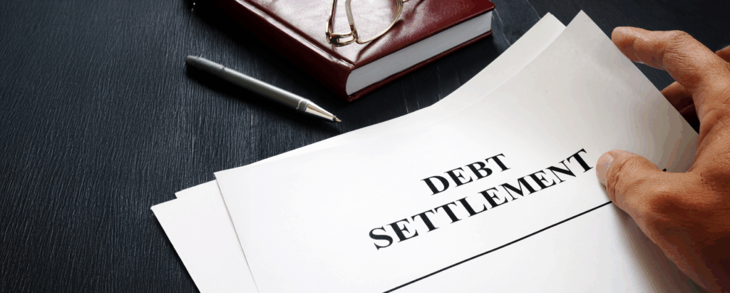Hand is holding Debt Settlement documents.