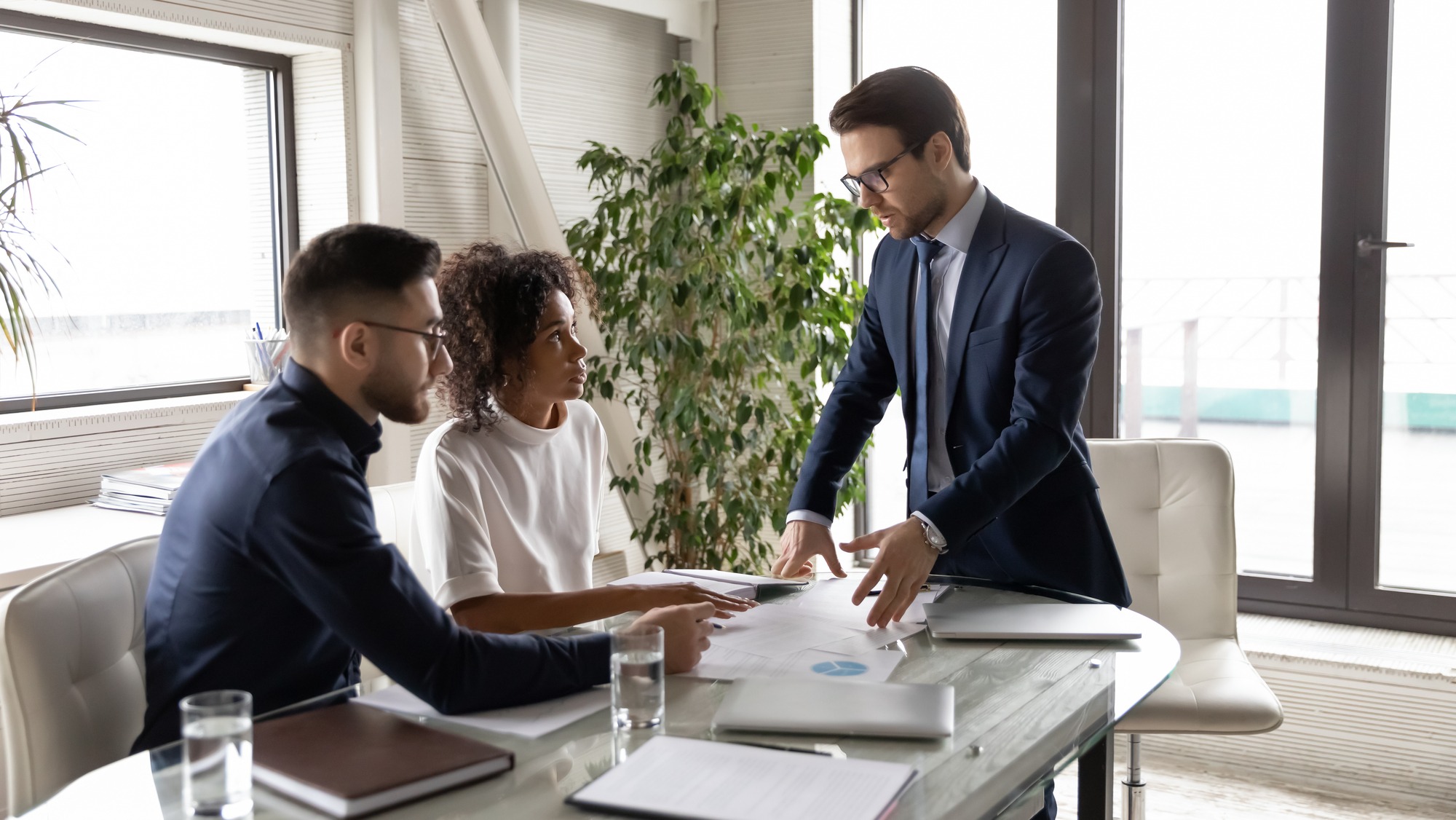 Concentrated multiracial business people gather at desk in boardroom.